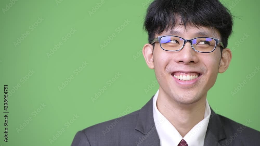 Young happy Asian businessman smiling while thinking Young happy Asian businessman smiling while thinking