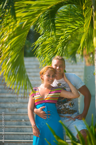 a man hugs a woman at a resort under palm leaves