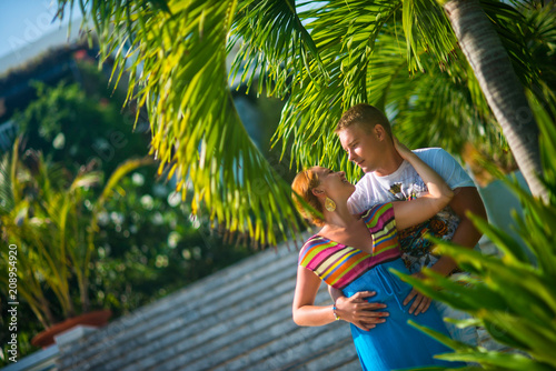 Happy couple in love stands on the background of palm trees and steps