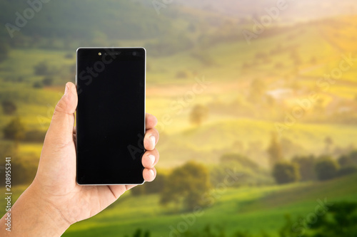 hand use smartphone with beautiful field in the blue sky photo