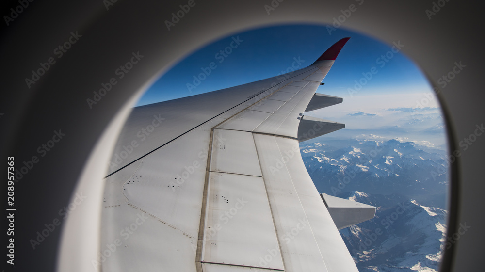 Snow mountain view in Europe with airplane wing through aircraft window Snow mountain view in Europe with airplane wing through aircraft window