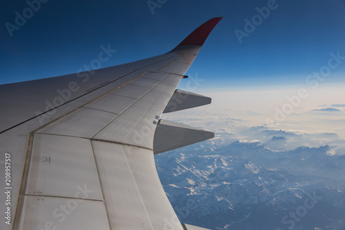 Snow mountain view in Europe with airplane wing through aircraft window
