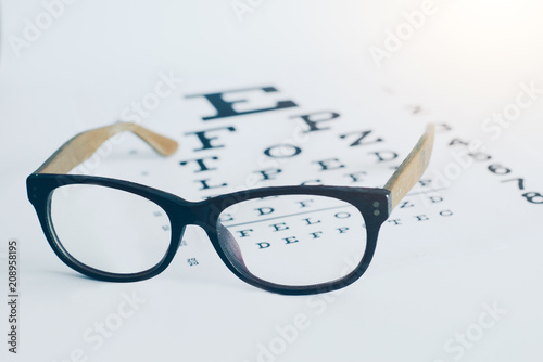 Eyeglasses on an optician visual text chart with white background. Eyesight optician concept