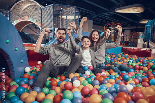 Glad family sitting in pool with balls photo