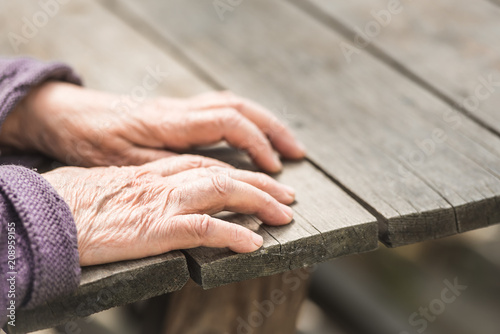 Old wrinkled female hands on a wooden table