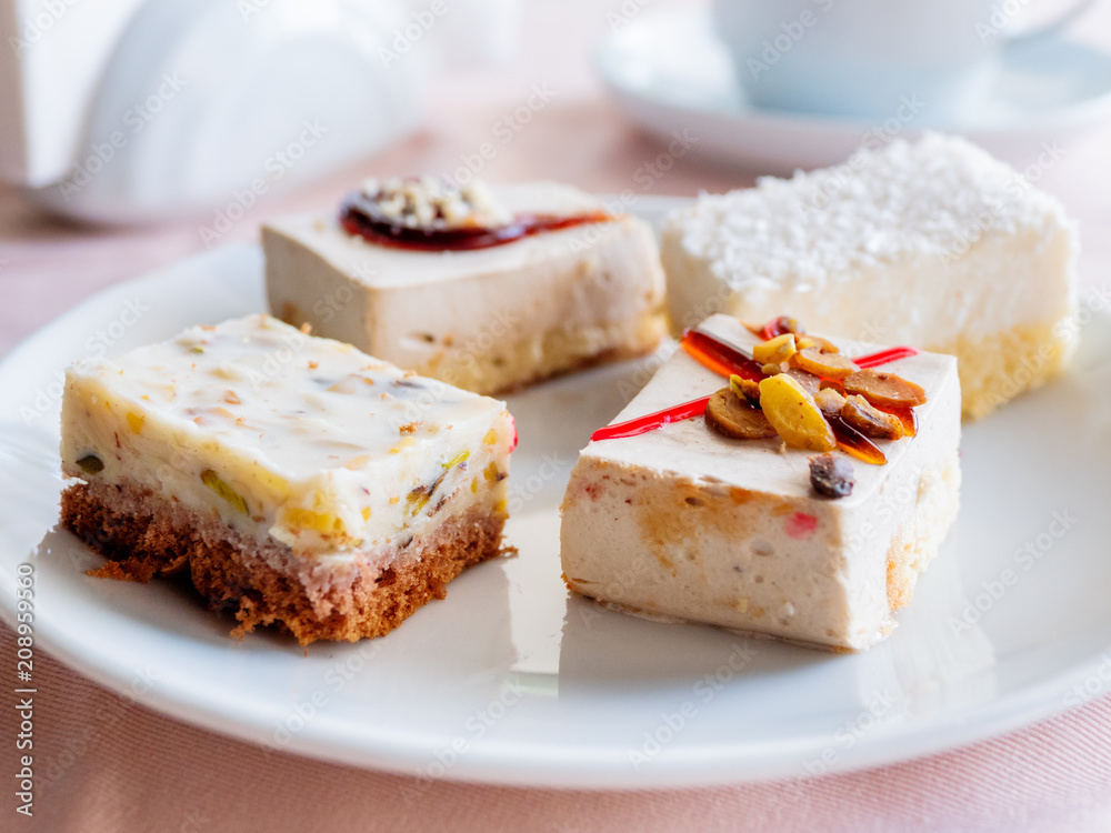 White plate full of different pastries. Tasty desserts with topping, coconut flakes.