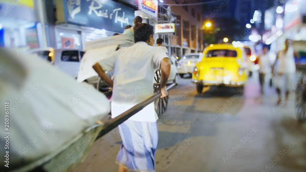 illuminated busy indian street at night time, back view following rickshaw going on street shoting on tilt-shift lens