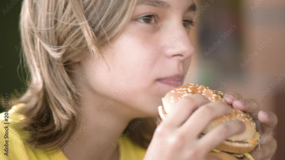 Young happy teenager eating tasty hamburger in fast food restaurant. Teen girl eating french fries for dinner at fast food cafe. Young happy teenager eating tasty hamburger in fast food restaurant. Teen girl eating french fries for dinner at fast food cafe.