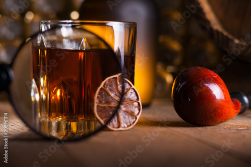 Glass of whiskey, magnifying glass, lemon and smooking pipe  photo