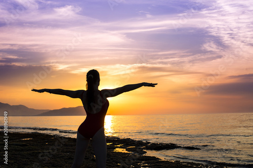 young girl practicing yoga on the beach during the sunset. © Stavros