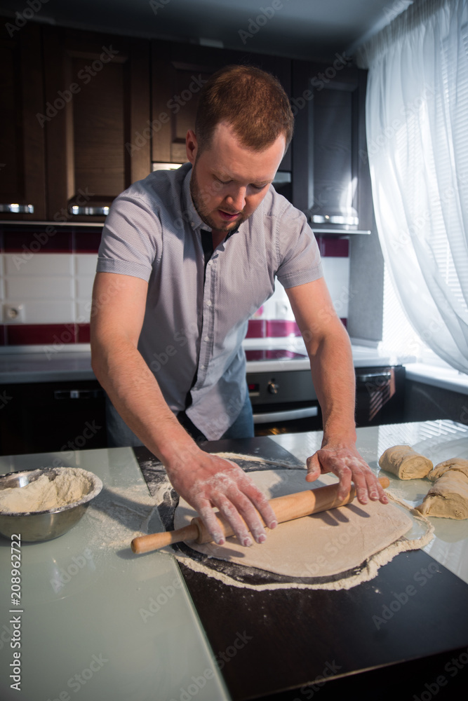 the man rolled out the dough with a rolling pin at home the man rolled out the dough with a rolling pin at home