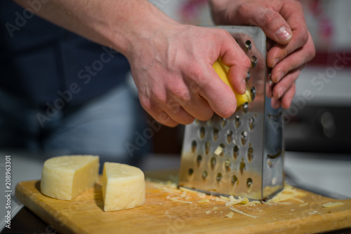 a man rubs cheese on a metal grater