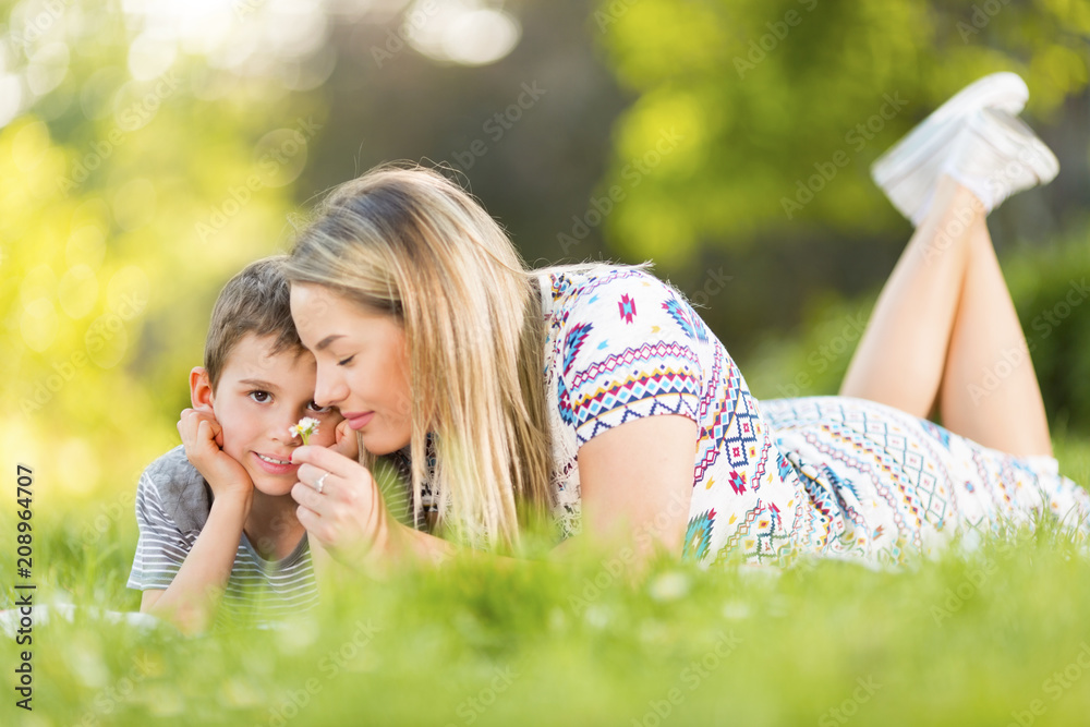 Mother and son smelling a flower in park Mother and son smelling a flower in park
