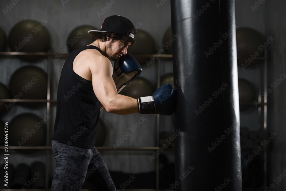 Muscular young boxer training with punching bag