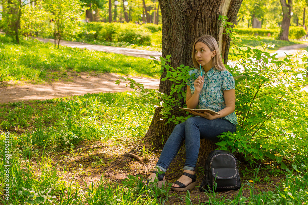 Beautiful young woman writing in her diary in the park Beautiful young woman writing in her diary in the park