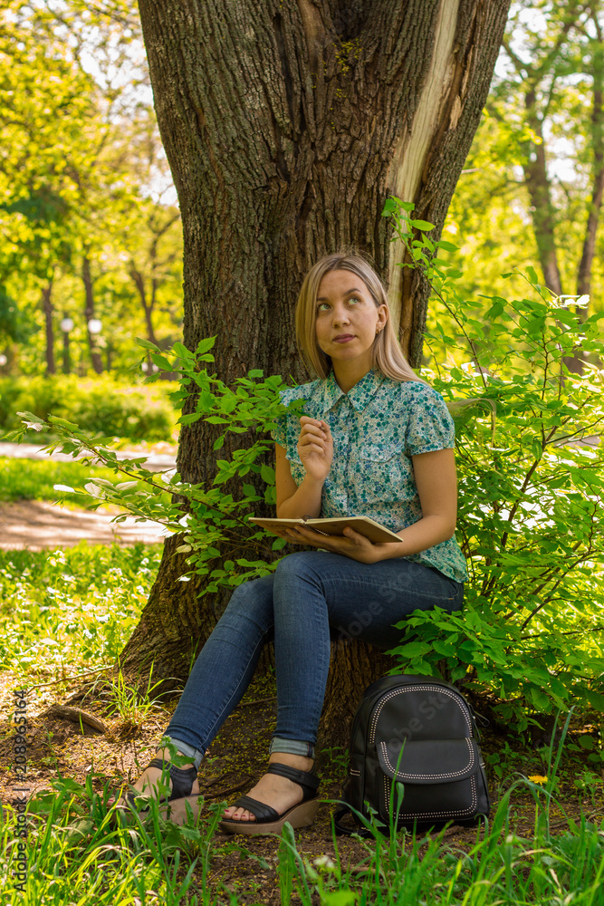 young woman writing in her diary in the park young woman writing in her diary in the park
