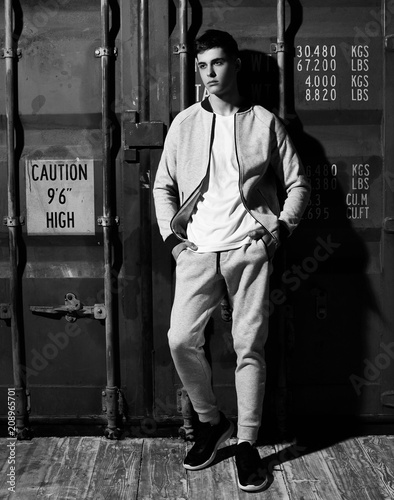 Young handsome sporty man in gary sport clothes posing against red metal doors of intermodal container photo