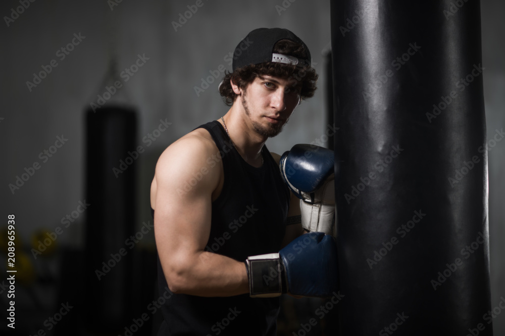 Young boxer posing next to punching bag
