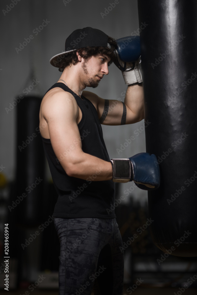Young boxer posing next to punching bag
