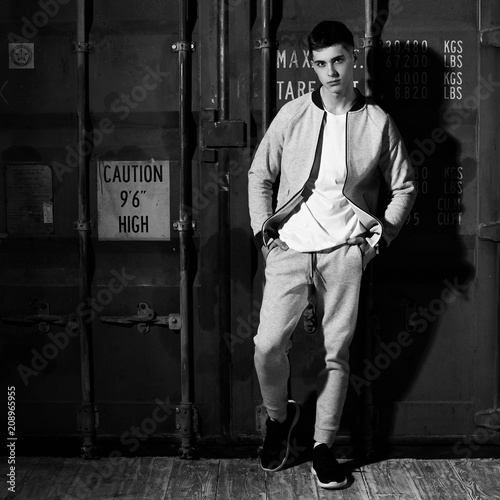 Young handsome sporty man in gary sport clothes posing against red metal doors of intermodal container photo