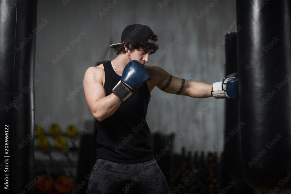 Muscular young boxer training with punching bag