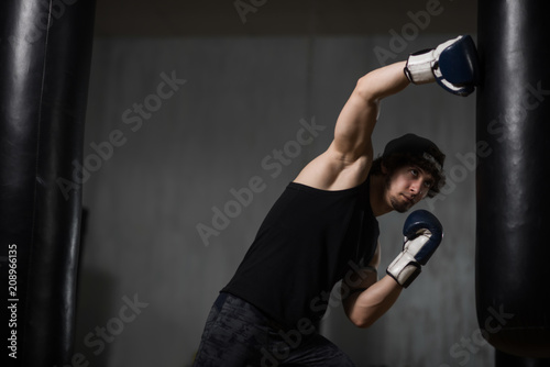 Muscular young boxer training with punching bag © Vladimir