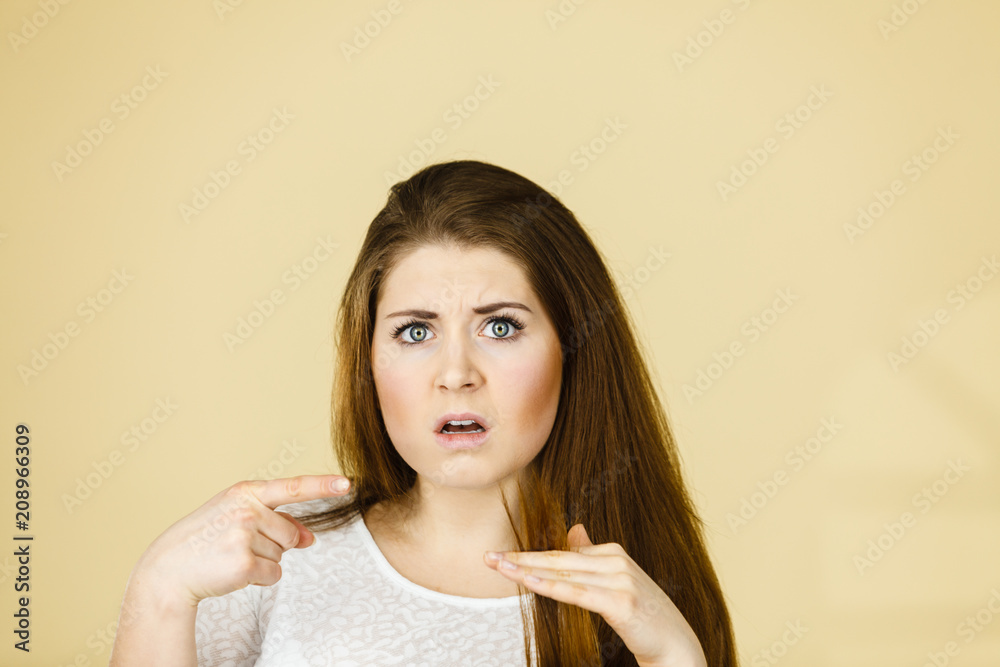 Worried woman looking at her dry hair ends Worried woman looking at her dry hair ends