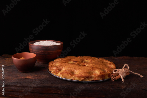 On a dark wooden table american apricot pie, ingredients and tools on black background photo