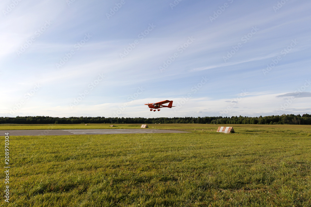 A small red airplane is landing. A small red airplane is landing.
