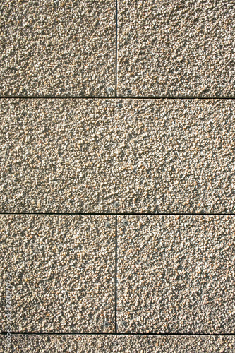 Fragment of an outdoor coating made of grey scabrous sand, closeup. Abstract grainy textured background.