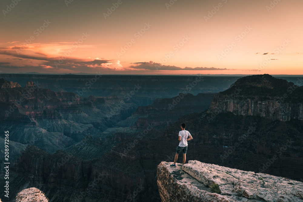 young man stays on the edge of Magnificent Grand Canyon, Arizona, USA.