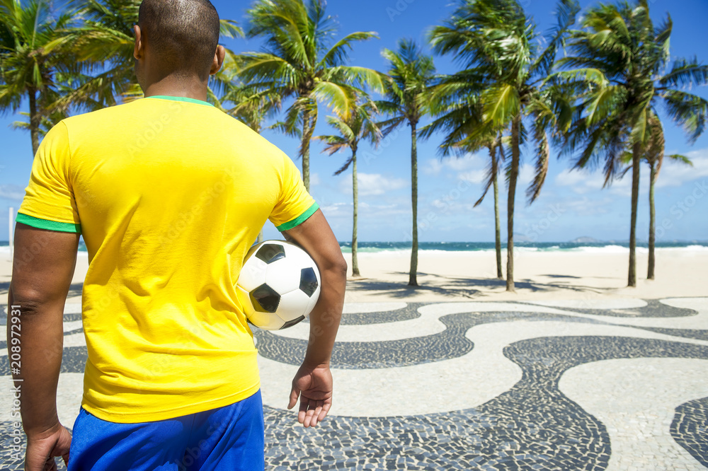 Brazilian soccer player holding football wears shirt in Brazil colors at Copacabana  beach, Rio de Janeiro. Stock Photo | Adobe Stock