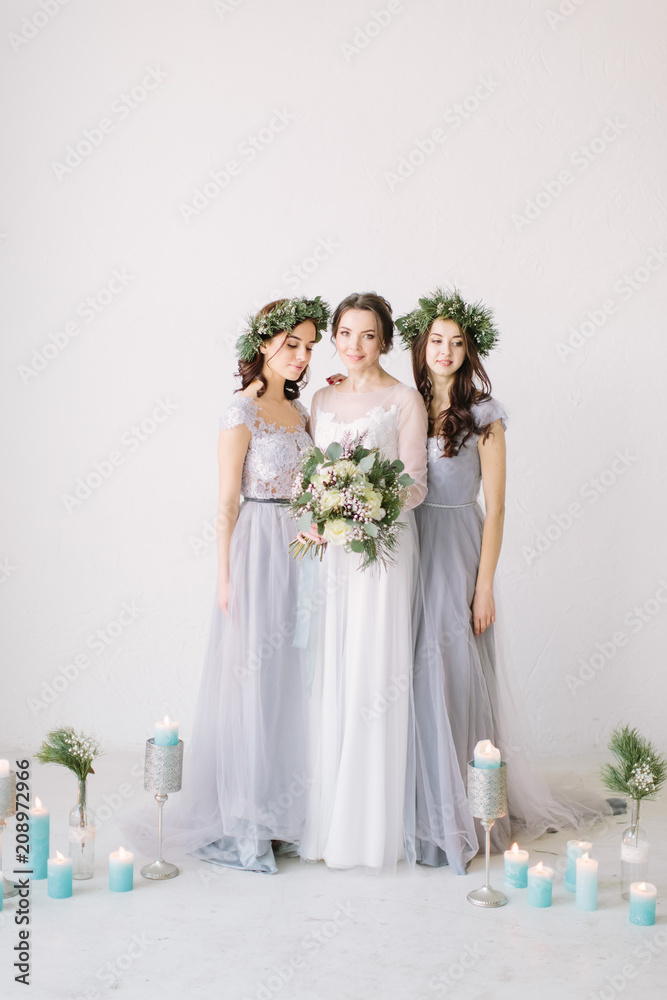 Happy bride in a white dress holds a wedding bouquet and poses with her  friends in elegant dresses. White room is decorated with pine, flowers and  blu Stock Photo - Alamy