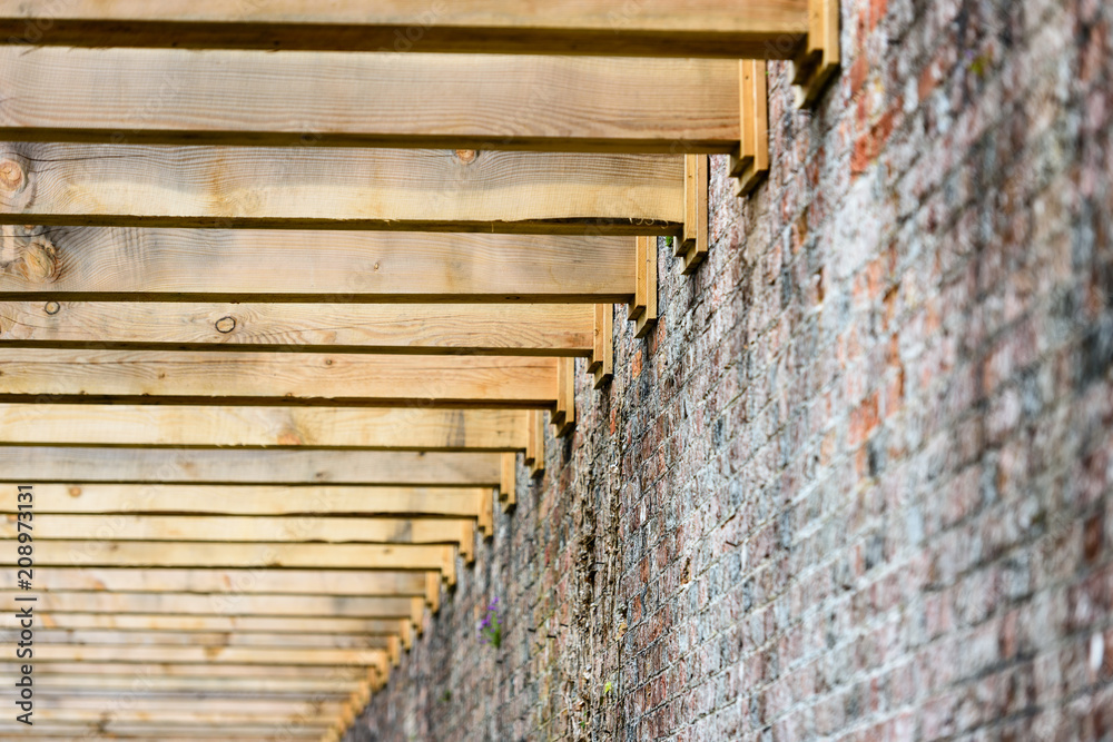 Heavy wooden beams of a newly constructed pergola attached to the brick