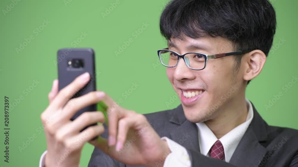 Young happy Asian businessman using phone and touching screen Young happy Asian businessman using phone and touching screen