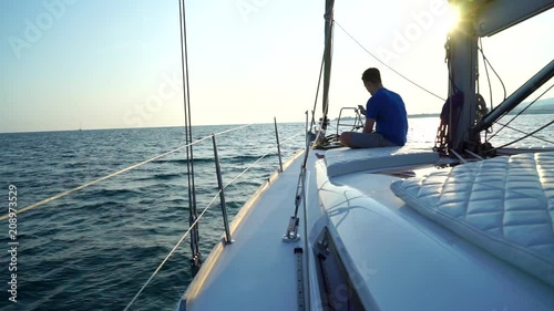 The Young Man Sits On The Yacht With Phone At Sunset