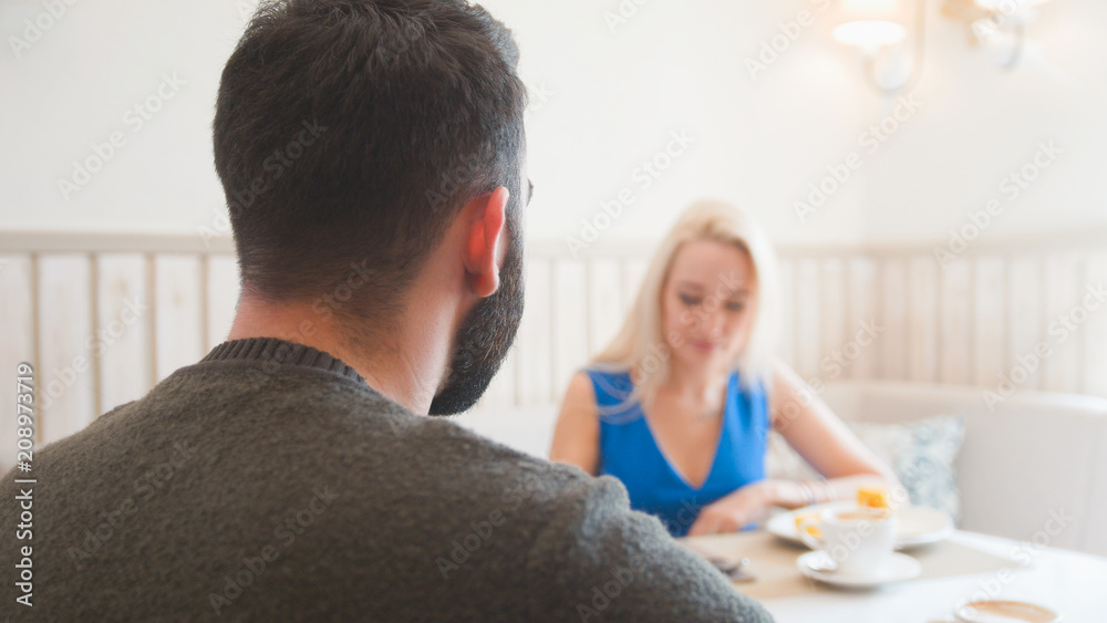 Fototapeta premium Happy caucasian couple takes desserts and talking at the cafe