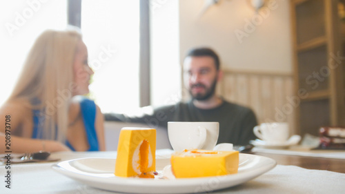 Young couple having lunch in cafe waitress passes - defocused