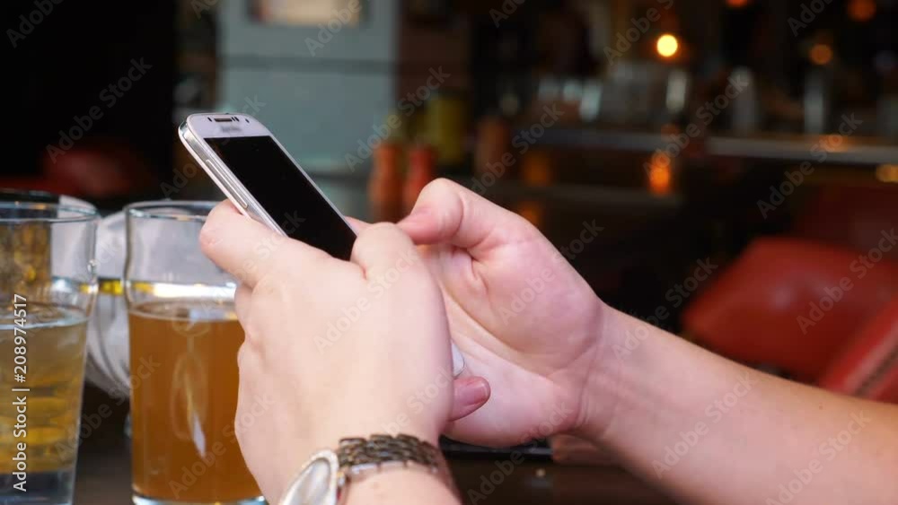 Woman using mobile phone at the bar in 4k slow motion 60fps