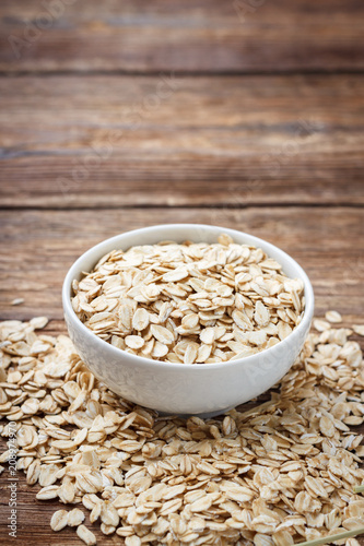 Dry rolled oat flakes oatmeal on wooden table