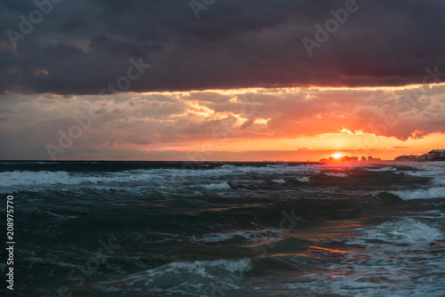 Dramatic magical dark orange red sunset in Santa Rosa Beach, Florida with Pensacola coastline coast cityscape skyline in panhandle with ocean gulf mexico waves © Kristina Blokhin