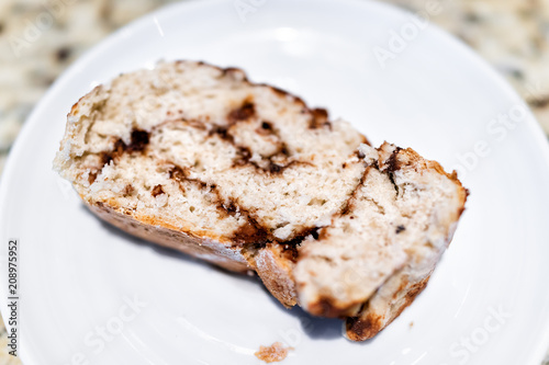 Macro closeup of homemade healthy vegan golden baked whole cinnamon roll cake slice bread on plate table