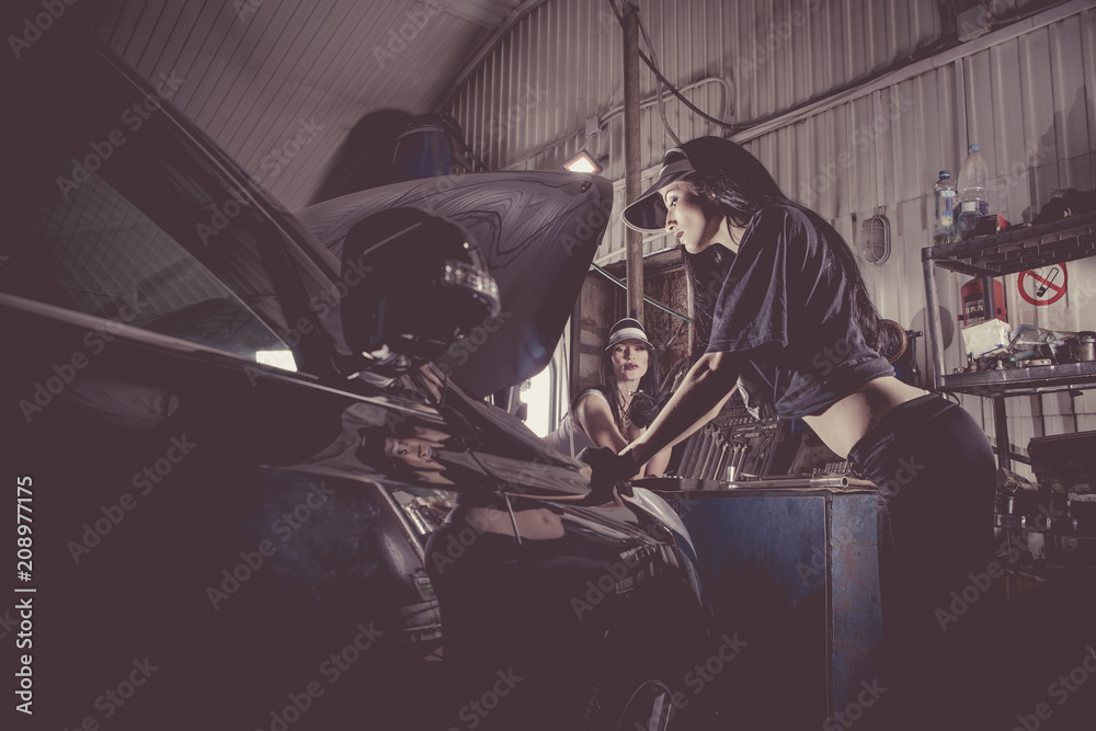 Women mechanics are inspecting the engine at the service station.