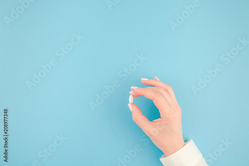 Female hand holding a white pill