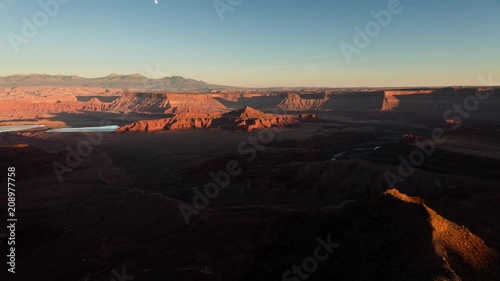 Sunset light moves over a plain and lakes below as seen from a lookout.