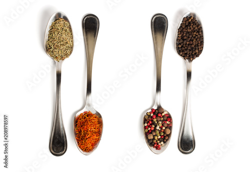 Different spices in iron spoons isolated on white