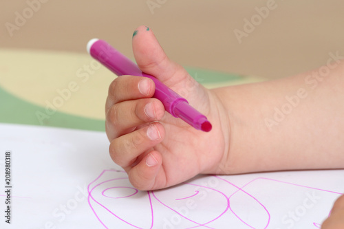 close up on the hand of a child who draws with colored markers