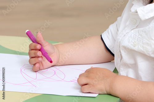 close up on the hand of a child who draws with colored markers