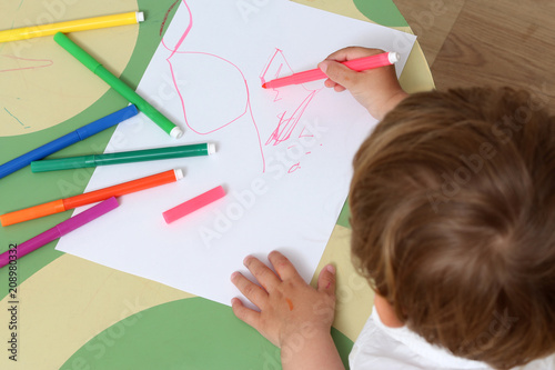 close up on the hand of a child who draws with colored markers