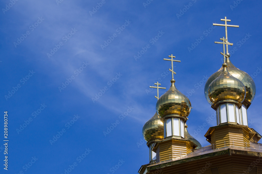 Golden domes and crosses of Russian orthodox church on blue sky background